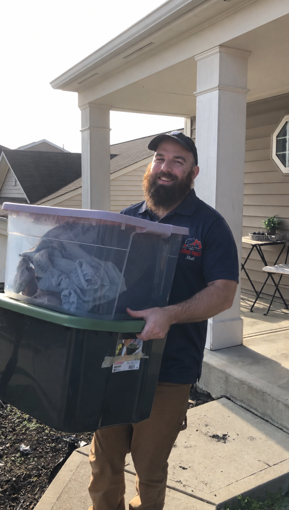Matt from Junk Dads carrying stacked storage totes off a front porch