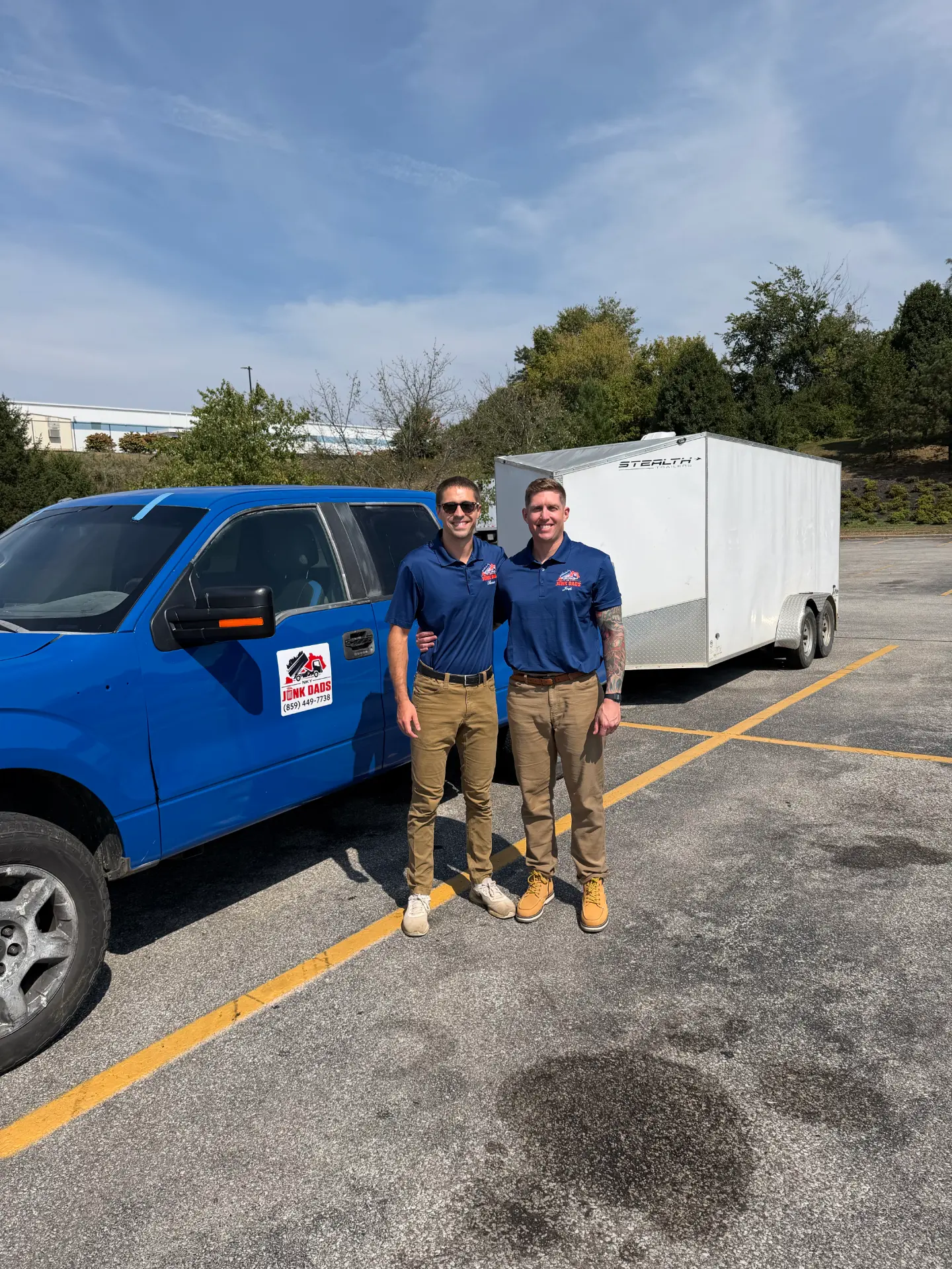 The NKY Junk Dads founders beside their blue truck and enclosed trailer